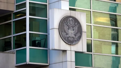 شعار الحكومة الأمريكية على واجهة مبنى زجاجي، يرمز إلى قضايا الهجرة والحقوق المدنية المتعلقة بترحيل الأطفال.