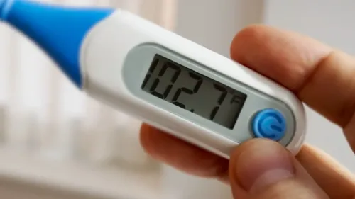 مقياس حرارة رقمي يظهر درجة حرارة 102.7 فهرنهايت، مما يشير إلى وجود حمى. الصورة تتعلق بأهمية الرعاية الصحية الوقائية.