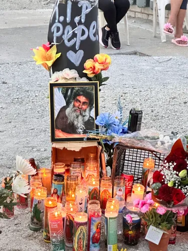 نصب تذكاري لبيبي، رجل مشرد قُتل في شيكاغو، يتضمن صورته، شموعًا مضاءة، وزهورًا، مع لافتة تحمل عبارة "ارقد بسلام".