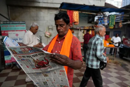 رجل يرتدي سترة برتقالية يقرأ صحيفة في سوق مزدحم، مع وجود أشخاص آخرين في الخلفية، مما يعكس التفاعل اليومي مع وسائل الإعلام في الهند.