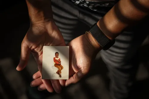 صورة تُظهر يدين تحملان صورة قديمة لطفل يجلس مبتسمًا، تعكس ذكريات كورنيليوس تايلور قبل معاناته مع التشرد.