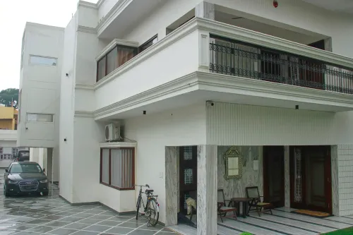 مبنى سكني في نيودلهي حيث تم القبض على رجل متهم بإدارة سفارة وهمية، مع سيارة فاخرة ودراجة في الساحة.