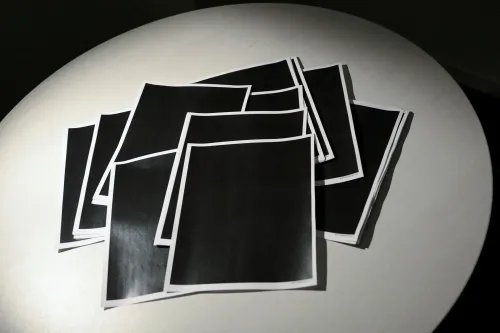 مجموعة من الأوراق المطبوعة باللون الأسود موضوعة على طاولة، تعكس حالة الغموض حول المعلومات المتعلقة بقضية جيفري إبستين.