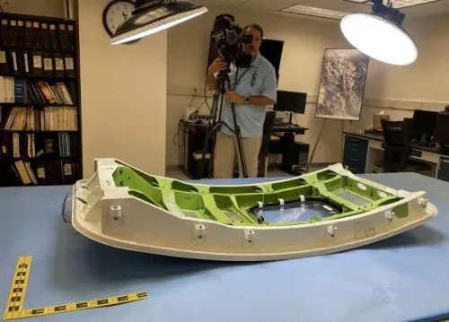 قطعة من هيكل طائرة تعرضت لثقب بسبب انفجار سدادة باب، مع مصور في الخلفية، تعكس مخاوف السلامة على متن الطائرات.