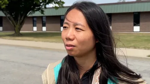 امرأة تتحدث أمام مبنى، تعبر عن مشاعرها بعد حادث حافلة سياحية في نيويورك، حيث أصيب العديد من الركاب.