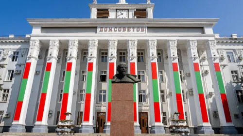 واجهة مبنى حكومي في ترانسنيستريا مزينة بألوان العلم الوطني، مع تمثال نصفي لشخصية تاريخية أمامه، تحت سماء زرقاء.