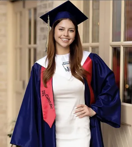 صورة لشابة ترتدي قبعة تخرج وزي تخرج رسمي، مبتسمة أمام مبنى، تمثل كاميلا ميندوزا أولموس المفقودة في سان أنطونيو.