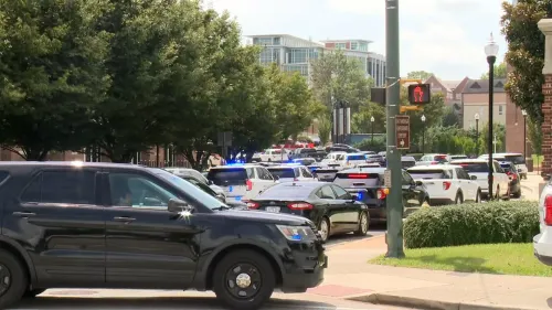 تظهر الصورة حشودًا من سيارات الشرطة في موقع حادثة أمنية بجامعة، حيث تتواجد عناصر إنفاذ القانون في حالة تأهب.