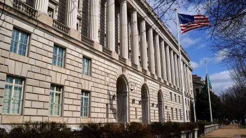 مبنى مصلحة الضرائب الأمريكية يظهر في الصورة مع العلم الأمريكي يرفرف، يعكس التغييرات الكبيرة في القوى العاملة والضغط على الموظفين.