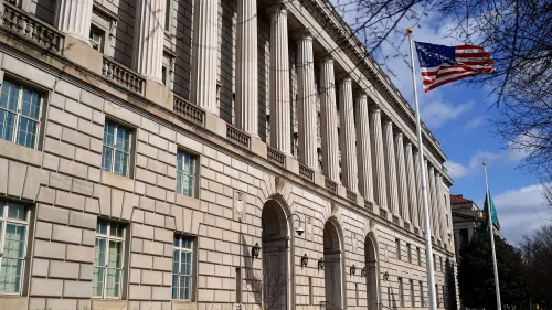 مبنى دائرة الإيرادات الداخلية الأمريكية مع أعمدة بارزة وعلم الولايات المتحدة يرفرف، يعكس التغييرات الإدارية والقرارات المثيرة للجدل في الوكالة.