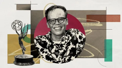 جيف هيلر مبتسم مع جائزة إيمي، محاط بألوان وخلفية فنية، يعكس لحظة فوزه وتأثيره في مسلسل "شخص ما في مكان ما".