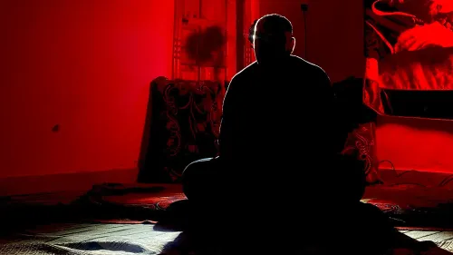 رجل يجلس في غرفة مظلمة بإسلام أباد، مع إضاءة خافتة تبرز ملامحه، يعكس شعور القلق والانتظار بعد انسحاب القوات الأمريكية من أفغانستان.