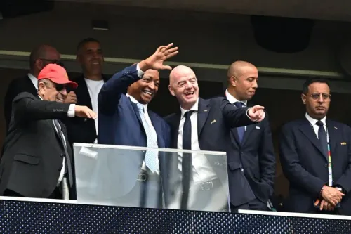رئيس FIFA جياني إنفانتينو يبتسم ويرحب مع مسؤولين أفارقة في مدرجات مباراة، مع دعم الاتحاد الأفريقي لكرة القدم له.