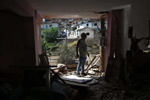 رجل يقف في مدخل منزل مدمّر في كاراكاس، محاطًا بالأنقاض، ينظر إلى الخارج حيث تظهر المباني في الخلفية.
