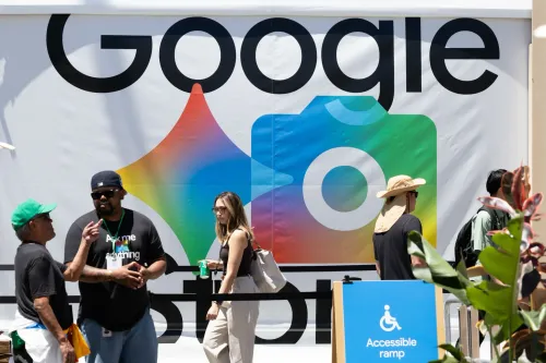 لافتة كبيرة تحمل شعار Google مع ألوان زاهية، بينما يتجمع عدد من الأشخاص في حدث تقني، مما يعكس تأثير الذكاء الاصطناعي في البحث.