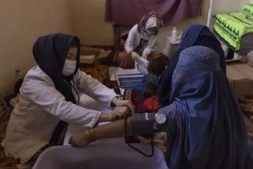 مقدمة مهنية لعلاج النساء الحوامل في عيادة صحية، حيث تقوم ممرضة بفحص ضغط الدم لامرأة ترتدي البرقع، مع وجود خدمات صحية خلفية.