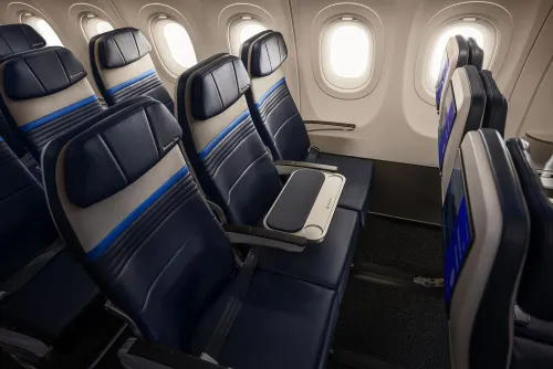 مقاعد طائرة United Airlines في قسم economy plus مع مساحة إضافية للمرفقين وطاولة وسطى محجوبة لتحسين راحة الركاب.