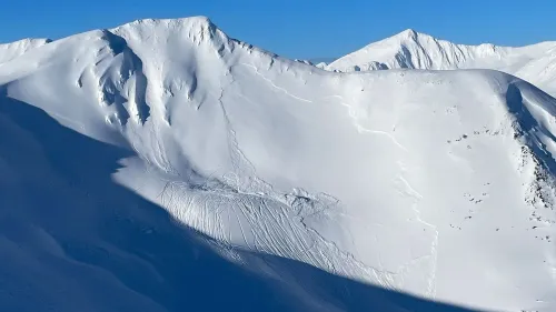 منحدر ثلجي في ألاسكا يظهر آثار انهيار جليدي مع مسارات تزلج، مما يعكس الظروف الخطرة التي أدت إلى حوادث مميتة.