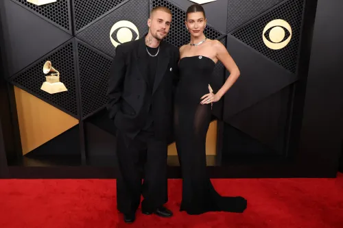 Justin Bieber وزوجته هايلي، يرتديان ملابس أنيقة، يقفان على السجادة الحمراء في حفل توزيع جوائز Grammy، مع تواجد جائزة Grammy خلفهما.