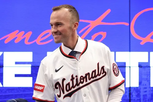 بليك بوتيرا مبتسم في مؤتمر تقديمه كمدير جديد لفريق واشنطن ناشونالز، مرتديًا قميص الفريق، مع خلفية تحمل اسم الفريق.