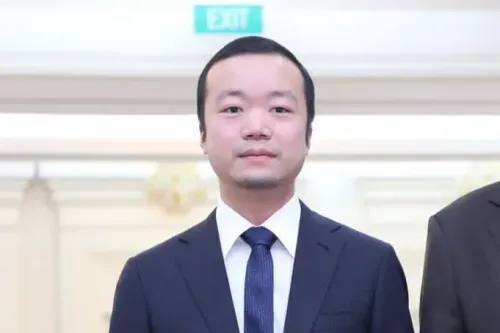 تشين تشي، رجل أعمال بارز، يرتدي بدلة رسمية، ويظهر في صورة رسمية، مرتبط بشبكة إجرامية عالمية في كمبوديا.