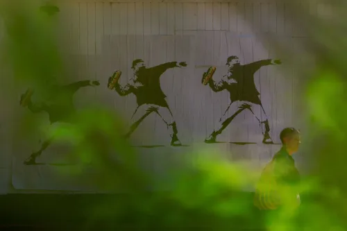 رجل يسير بجانب جدارية تُظهر شخصًا يلقي بشطيرة، تعبيرًا عن الاحتجاج، في سياق قضية جنائية في واشنطن.