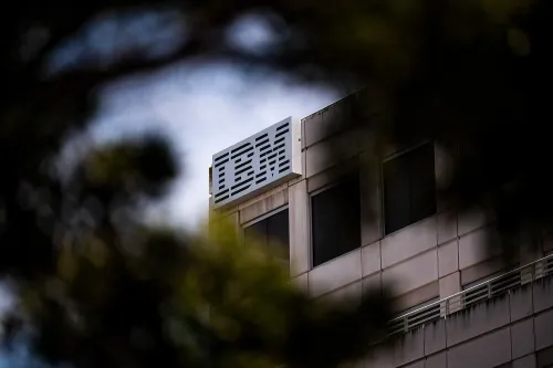 شعار شركة IBM يظهر على مبنى، مع التركيز على التغييرات التنظيمية في صناعة التكنولوجيا وتأثيرها على تسريح العمال.