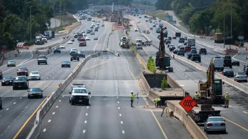 مشهد لطرق مزدحمة أثناء أعمال البناء، مع وجود عمال ومعدات ثقيلة. يعكس التحسينات في البنية التحتية الأمريكية.