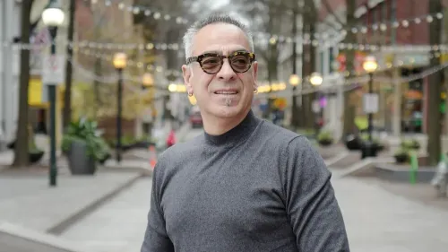 جورج غليزمان، المواطن الأمريكي الذي أُطلق سراحه بعد عامين في أفغانستان، يظهر مبتسمًا في شارع مزدحم، مع أضواء في الخلفية.