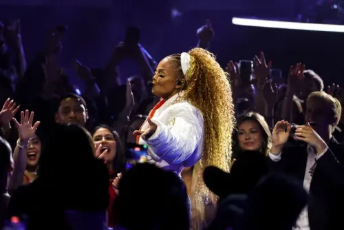 جانيت جاكسون تؤدي على المسرح في حفل توزيع جوائز الموسيقى الأمريكية، مع تفاعل حماسي من الجمهور حولها.