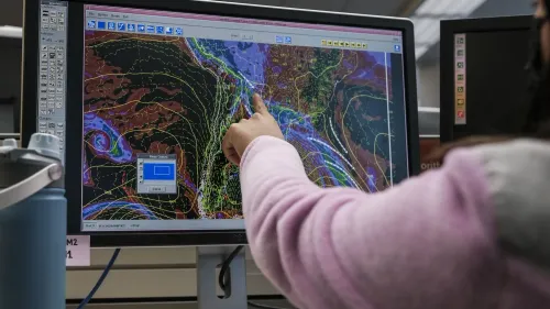 شخص يشير إلى شاشة حاسوب تعرض بيانات الأرصاد الجوية والخرائط، في سياق تأثير الإقالات داخل الإدارة الوطنية للمحيطات والغلاف الجوي.