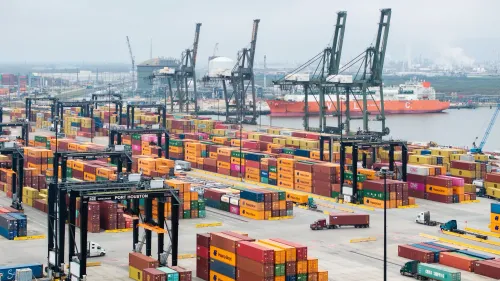 مستودع حاويات في ميناء هيوستن، يظهر حاويات ملونة وشاحنات، مما يعكس تأثير التعريفات الجمركية على التجارة الأمريكية.