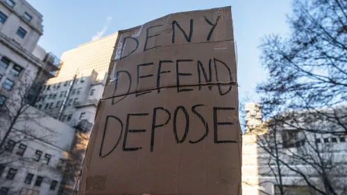 لافتة مكتوبة عليها \"DENY DEFEND DEPOSE\" تظهر في خلفية حضرية، تعكس الاستياء من شركات التأمين بعد حادثة قتل رئيس تنفيذي.