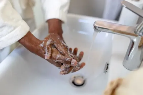 شخص يغسل يديه بالصابون تحت صنبور ماء جار، مما يعكس أهمية غسل اليدين للوقاية من الأمراض، كما ورد في دراسة جديدة.
