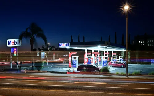 محطة وقود موبيل مضاءة في الليل، تظهر أسعار البنزين المرتفعة، تعكس تأثير التضخم على تكاليف المعيشة.