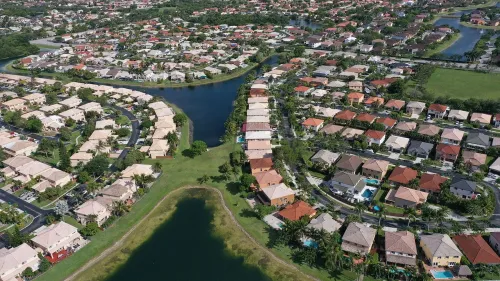 منظر جوي لحي سكني يتضمن منازل متعددة الأشكال والألوان، مع بحيرات وقنوات مائية، يعكس تأثير إدارة الإسكان الفيدرالية على ملكية المنازل.