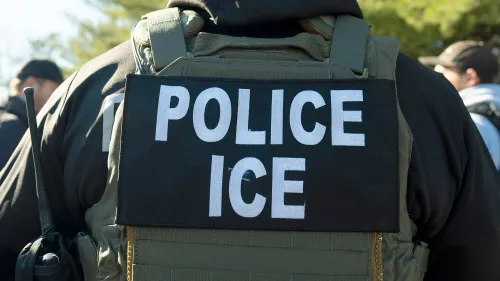 عميل من وكالة إنفاذ قوانين الهجرة والجمارك (ICE) يرتدي سترة تحمل كلمة "شرطة" أثناء مداهمة في حقل زراعي بكاليفورنيا.