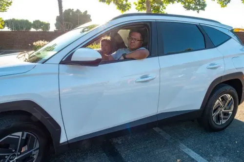 رجل وطفل يجلسان في سيارة بيضاء حديثة، مع أشجار في الخلفية، يعكسان تحديات الشراء في ظل ارتفاع الأسعار.