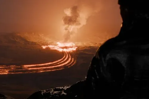 تظهر الصورة ثوران بركاني في أيسلندا، حيث تتدفق الحمم البركانية اللامعة مع تصاعد الدخان في الخلفية، مما يعكس قوة الطبيعة.