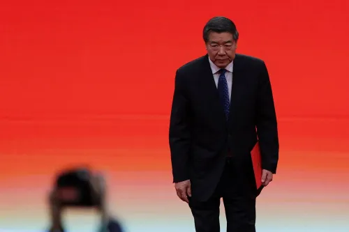 رجل يرتدي بدلة رسمية يسير نحو المنصة أمام خلفية حمراء، مع التركيز على استعداده للمفاوضات التجارية بين الصين والولايات المتحدة.