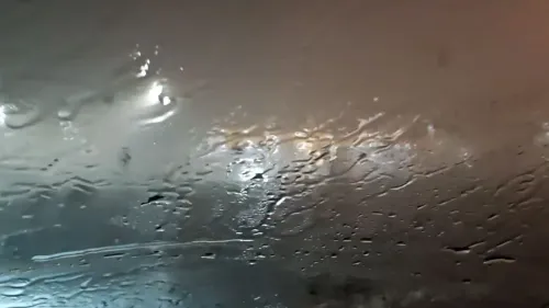 مياه تتساقط بغزارة على زجاج سيارة، مع أضواء خلفية مضببة، تعكس الظروف العاصفة التي شهدها الغرب الأوسط.