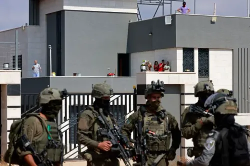 جنود إسرائيليون مسلحون يقفون أمام منازل فلسطينية محاصرة في قرية قصرة بالضفة الغربية وسط تصاعد العنف الاستيطاني.