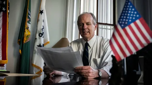 ديفيد ليبريك، مسؤول سابق في وزارة الخزانة، يتسلم جائزة تقديرية في حفل تكريم للموظفين الفيدراليين، مع العلم الأمريكي في الخلفية.