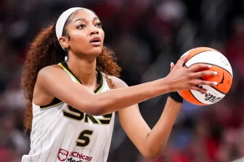 لاعبة كرة السلة أنجل ريس تستعد لإطلاق الكرة خلال مباراة، تعبيرها يظهر التركيز والإصرار في ظل دعم فريقها بعد حادثة إساءة.