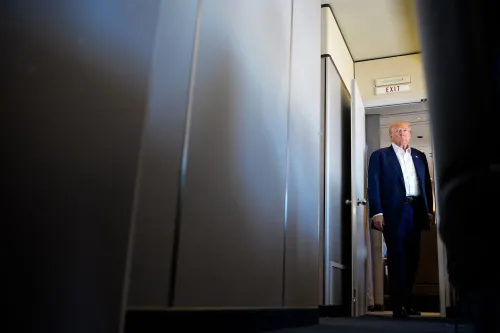 دونالد ترامب يمشي في ممر طائرة، مع إضاءة خافتة، مما يعكس حالة من التوتر والجدل حول قضايا قانونية تتعلق به.
