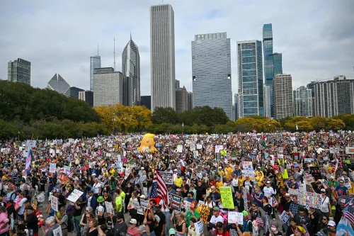 مظاهرة حاشدة في شيكاغو تضم آلاف المشاركين يحملون لافتات تعبر عن آراء سياسية متنوعة، مع خلفية ناطحات السحاب.