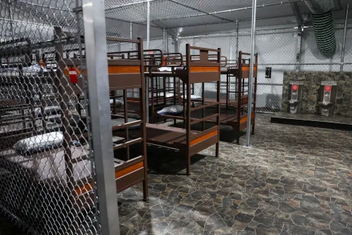 منشأة احتجاز المهاجرين في إيفرجليدز، مع أسرة بطابقين محاطة بسياج معدني، تعكس الوضع الحالي للقضية القانونية حول إغلاقها.