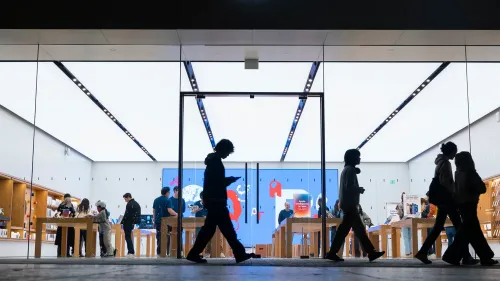 واجهة متجر Apple مع زبائن يتصفحون الأجهزة، مما يعكس الاهتمام المتزايد بالإصدارات الجديدة مثل iPhone النحيف المتوقع.