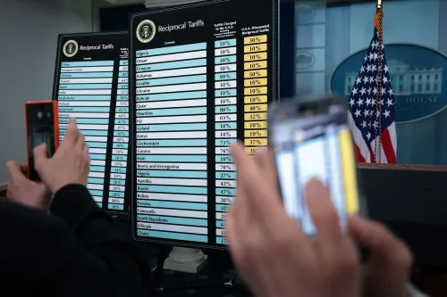 قائمة التعريفات الجمركية المتبادلة تظهر الرسوم المفروضة على صادرات الدول إلى الولايات المتحدة، مع تصوير شخص يستخدم هاتفه لتوثيق المعلومات.