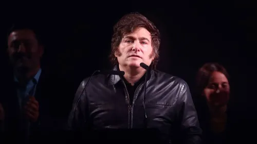 خافيير ميلي، رئيس الأرجنتين، يتحدث أمام الجمهور، مرتديًا سترة جلدية، وسط أضواء خافتة، مع وجود متحدثين خلفه.